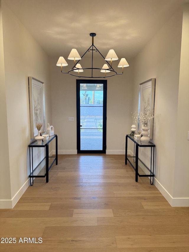 interior space with baseboards, an inviting chandelier, and light wood-type flooring