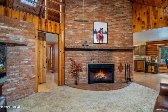 living area with carpet, a high ceiling, wood walls, wood finished floors, and a fireplace