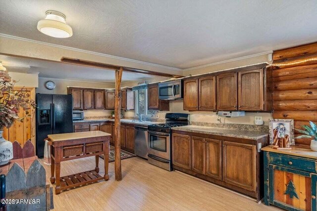 kitchen featuring ornamental molding, log walls, stainless steel appliances, and light wood-style floors