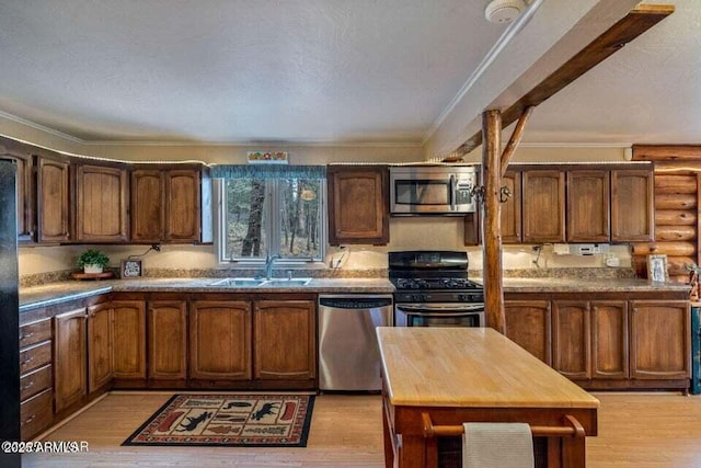 kitchen with light wood-style flooring, ornamental molding, stainless steel appliances, and a sink