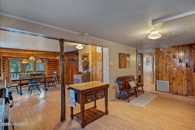 interior space featuring ornamental molding, light wood-style floors, visible vents, and a textured ceiling