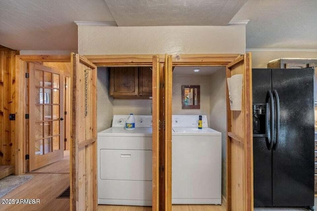 laundry area featuring light wood finished floors, washer and clothes dryer, a textured ceiling, and cabinet space