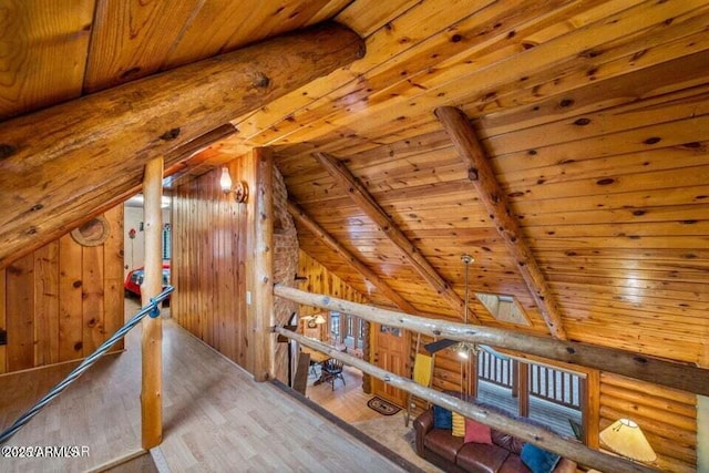 additional living space with wooden walls, wood finished floors, vaulted ceiling with beams, and wood ceiling