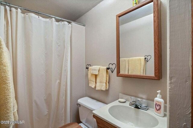 full bath with a shower with curtain, vanity, and toilet