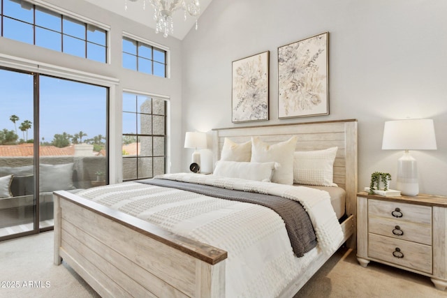 bedroom featuring light carpet, access to exterior, a towering ceiling, and a chandelier