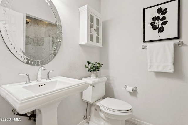 bathroom with baseboards, toilet, and a sink