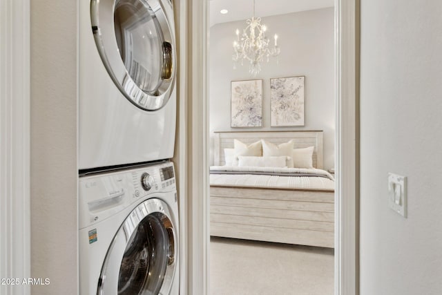 clothes washing area featuring stacked washer and clothes dryer and a chandelier