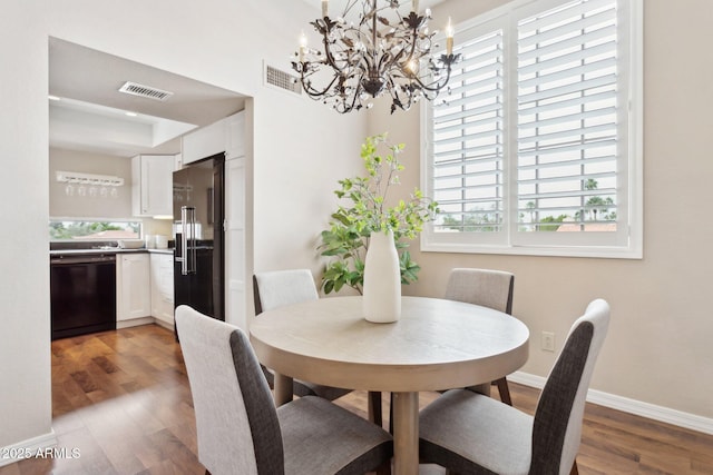 dining area featuring a chandelier, plenty of natural light, wood finished floors, and baseboards