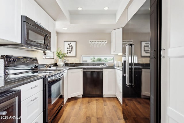 kitchen with black appliances, a tray ceiling, beverage cooler, white cabinets, and dark countertops