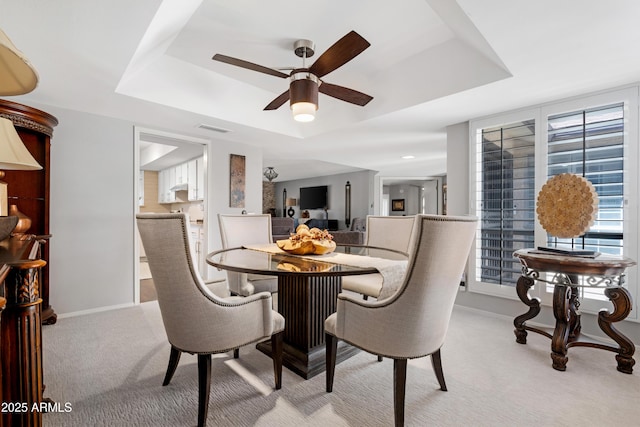 9621 E Calgary Ave, Sun Lakes, AZ 85248 - dining space with a tray ceiling, light carpet, ceiling fan, and baseboards