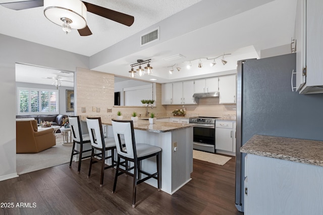 9621 E Calgary Ave, Sun Lakes, AZ 85248 - kitchen featuring stainless steel appliances, a ceiling fan, under cabinet range hood, a kitchen breakfast bar, and dark wood-style flooring