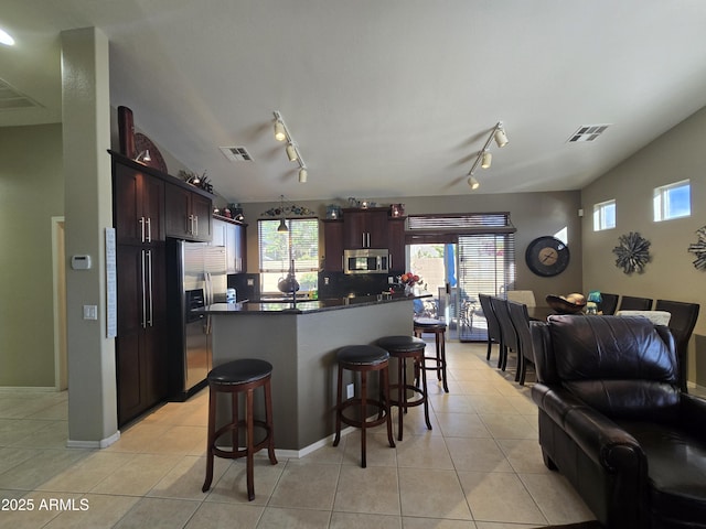 kitchen with light tile patterned floors, vaulted ceiling, stainless steel appliances, and a kitchen island