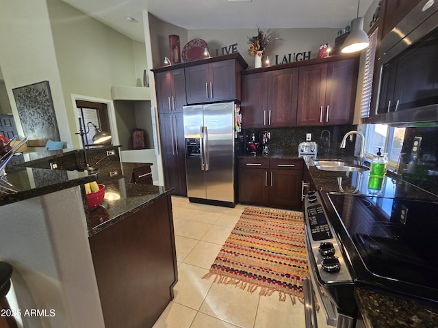 kitchen featuring pendant lighting, sink, light tile patterned floors, appliances with stainless steel finishes, and dark stone counters