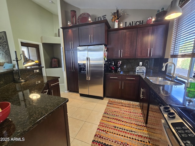 kitchen featuring sink, dark stone countertops, backsplash, light tile patterned floors, and stainless steel appliances