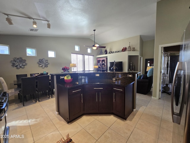 kitchen featuring an island with sink, light tile patterned floors, and dark brown cabinetry