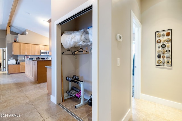 hallway featuring light tile patterned floors and lofted ceiling with beams