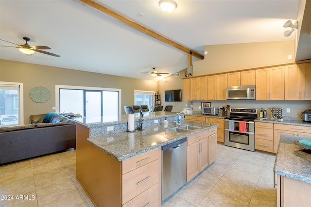 kitchen featuring sink, stainless steel appliances, vaulted ceiling with beams, an island with sink, and light brown cabinetry