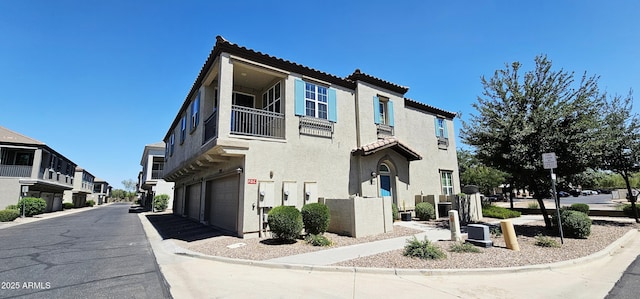 4705 E Red Oak Ln Unit 101, Gilbert, AZ 85297 - view of property exterior featuring a balcony, a garage, a tiled roof, and stucco siding