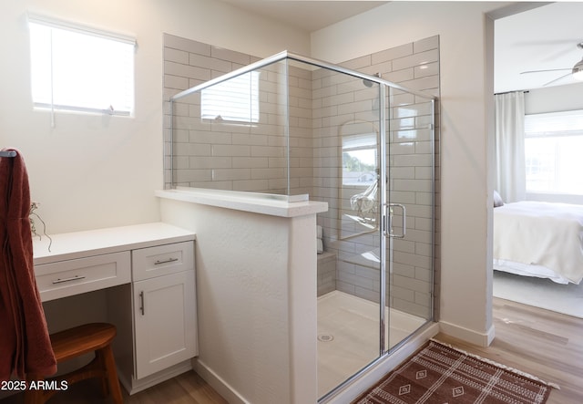 bathroom with hardwood / wood-style flooring, walk in shower, and ceiling fan