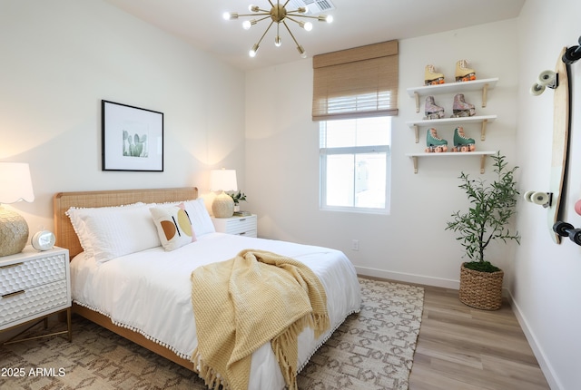 bedroom with light hardwood / wood-style flooring and an inviting chandelier