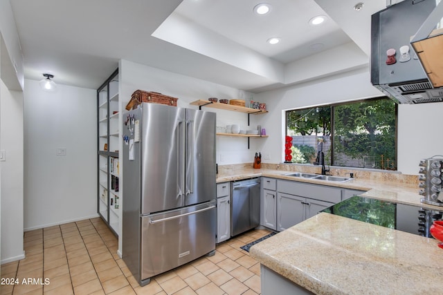 kitchen featuring gray cabinetry, sink, light tile patterned floors, a tray ceiling, and stainless steel appliances