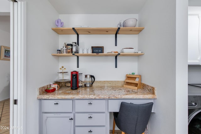 bar featuring light stone counters, white cabinetry, and washer / clothes dryer