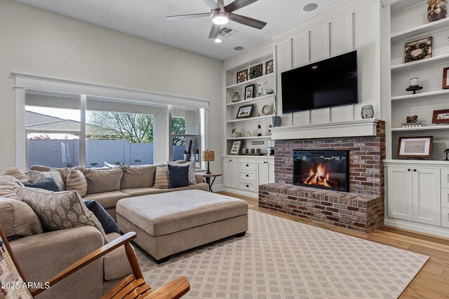 1439 E Mead Dr, Gilbert, AZ 85298 - living room with built in shelves, light wood-type flooring, ceiling fan, and a fireplace