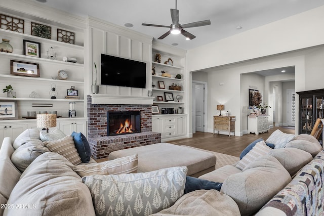 1439 E Mead Dr, Gilbert, AZ 85298 - living area with baseboards, wood finished floors, a ceiling fan, a brick fireplace, and built in shelves