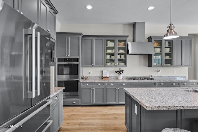 1439 E Mead Dr, Gilbert, AZ 85298 - kitchen with stainless steel appliances, wall chimney exhaust hood, light wood-type flooring, decorative light fixtures, and recessed lighting