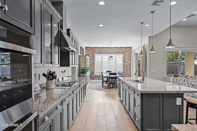 1439 E Mead Dr, Gilbert, AZ 85298 - kitchen with a sink, light wood-type flooring, plenty of natural light, brick wall, and light stone counters