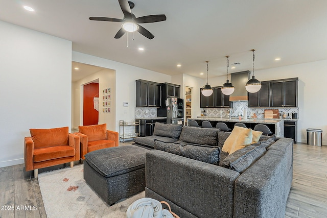 living area with light wood-style flooring, recessed lighting, and a ceiling fan