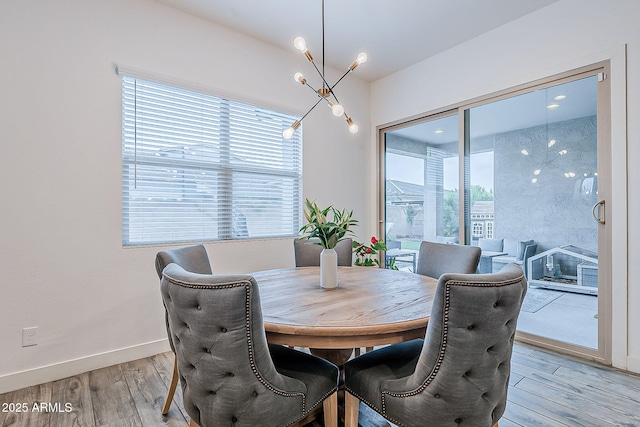 dining space with baseboards, an inviting chandelier, and light wood-style flooring