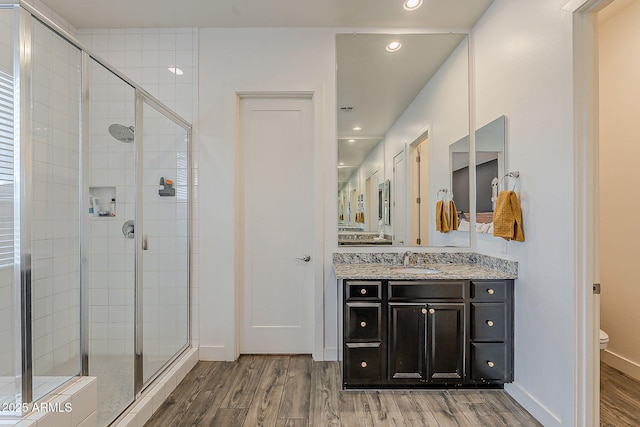 full bath featuring vanity, toilet, wood finished floors, and a stall shower