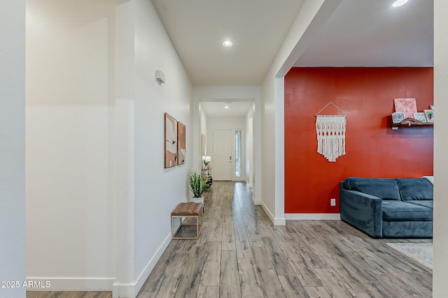 corridor with recessed lighting, baseboards, wood finished floors, and an accent wall