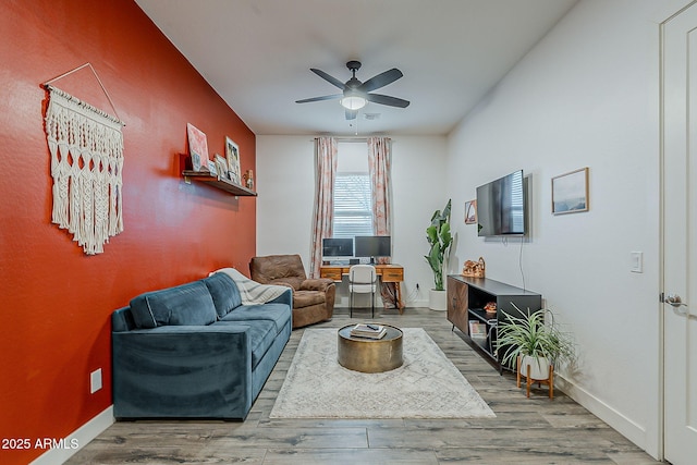 living area featuring baseboards, wood finished floors, and a ceiling fan