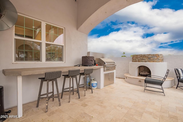 view of patio / terrace featuring exterior fireplace, area for grilling, and outdoor wet bar