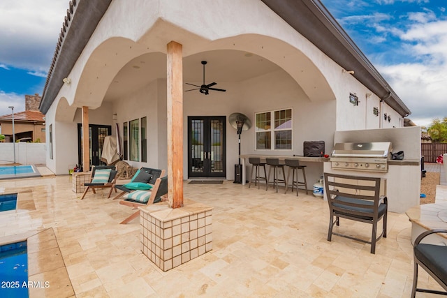 view of patio featuring area for grilling, fence, french doors, outdoor wet bar, and ceiling fan