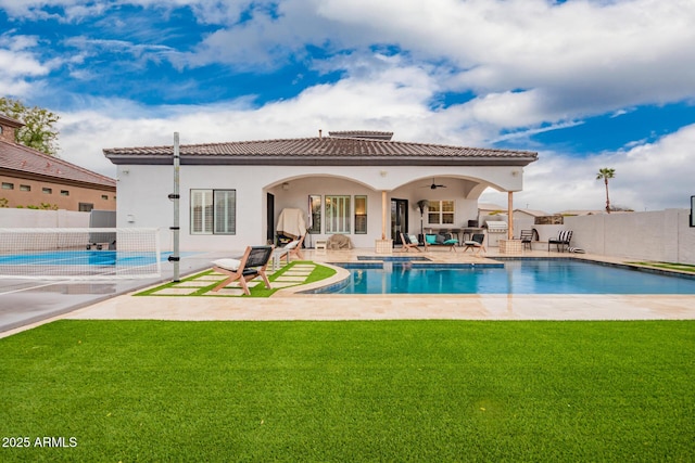 rear view of house with a lawn, a tile roof, a patio, and fence