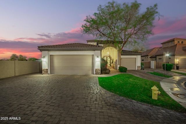 view of front of property featuring stone siding, stucco siding, a tiled roof, and decorative driveway