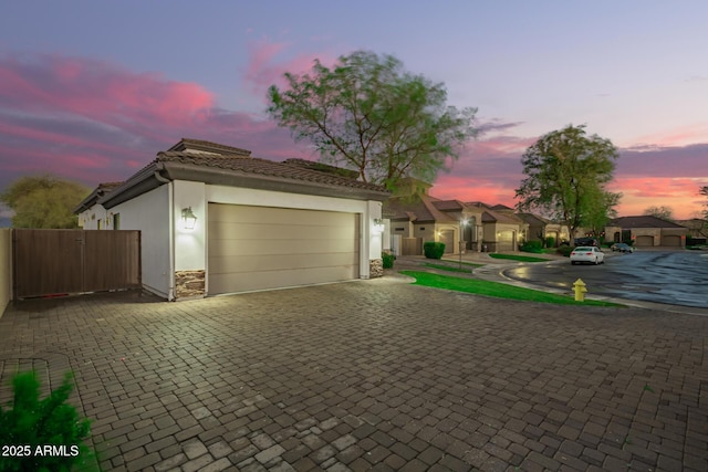 view of front of house with a tiled roof, stucco siding, driveway, and a gate