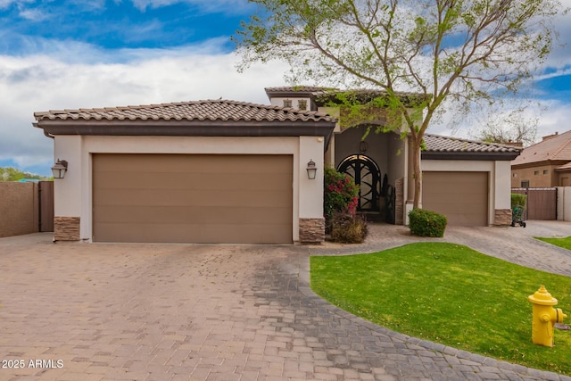 mediterranean / spanish-style home with an attached garage, fence, a tiled roof, stone siding, and driveway