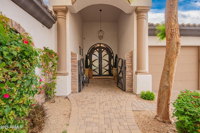 property entrance with an attached garage, stone siding, and stucco siding