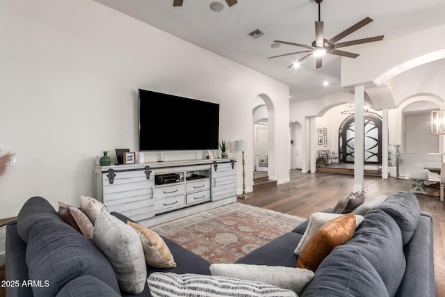 living room featuring arched walkways, visible vents, ceiling fan, and wood finished floors