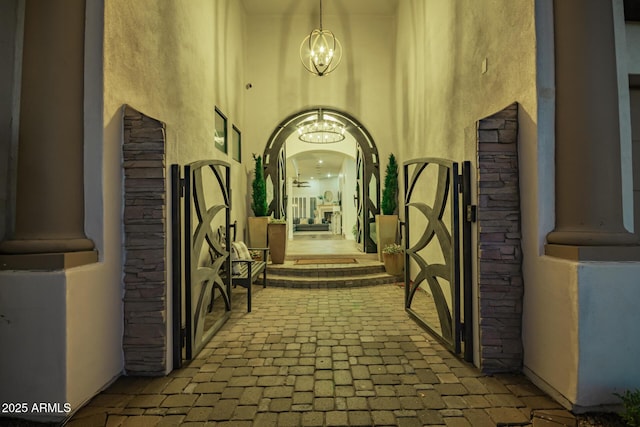 hall with a notable chandelier, brick floor, and a towering ceiling