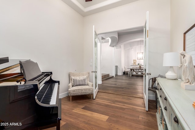 living area featuring baseboards, arched walkways, and wood finished floors