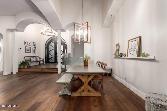 dining area with baseboards, arched walkways, a notable chandelier, and hardwood / wood-style flooring