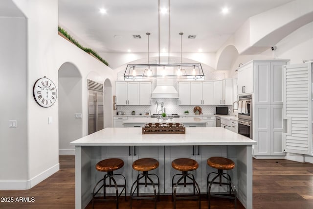 kitchen with visible vents, backsplash, appliances with stainless steel finishes, white cabinetry, and dark wood-style flooring