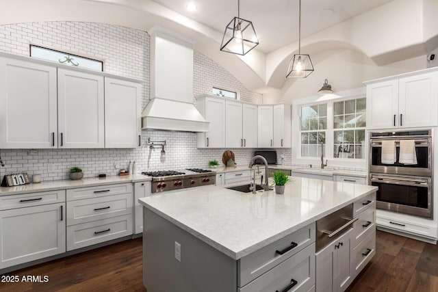 kitchen featuring backsplash, dark wood-type flooring, custom exhaust hood, stainless steel appliances, and a sink