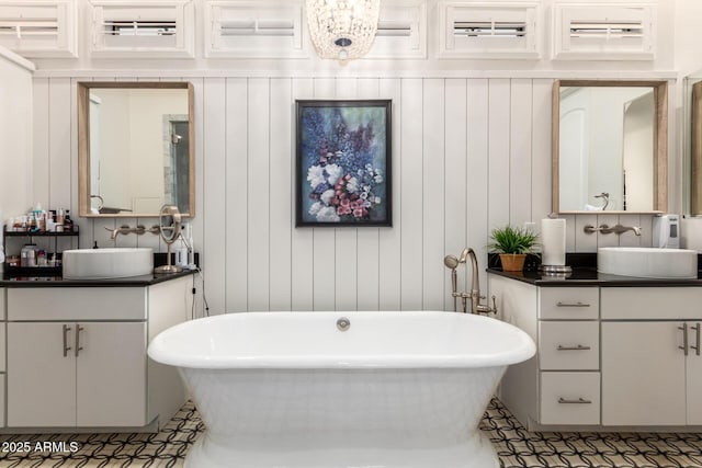 bathroom featuring a freestanding tub, two vanities, and a sink