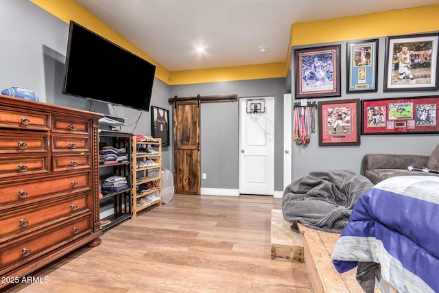 bedroom featuring light wood-type flooring, a barn door, and baseboards